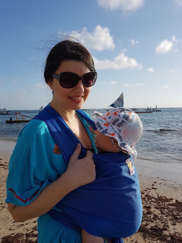 Josie Zecchinelli na praia com o filho em sling dry fit azul